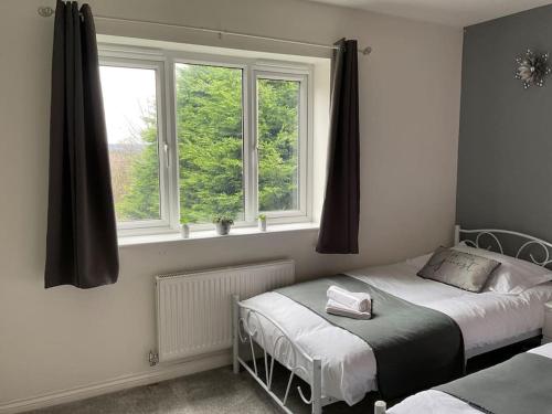 a bedroom with two beds and two windows at The WestField in Liversedge