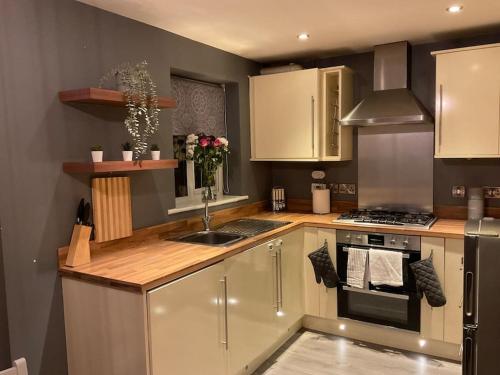 a kitchen with white cabinets and a sink and a stove at The WestField in Liversedge