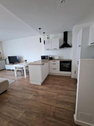 une cuisine avec des armoires blanches et un plancher en bois dans l'établissement Appartement cosy à 5 min des plages, à Hyères