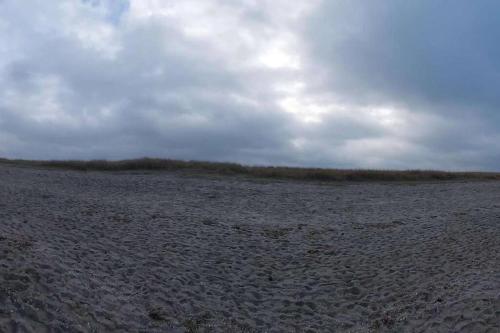 an empty field with a cloudy sky in the background at FeWo Nordsee Whng 3 in Wangerland