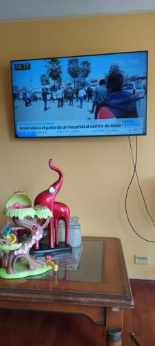 einen Tisch mit einem Dinosaurier-Spielzeug und einen TV an der Wand in der Unterkunft Dpto Empart 5 in Arica