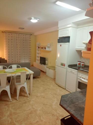 a kitchen and living room with a table and a refrigerator at Relájate en pareja o familia!!! in Tavernes de Valldigna