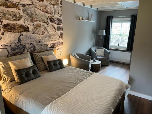 a bedroom with a large bed and a stone wall at B&B Hoeve Fraai Achterhoek in Aalten