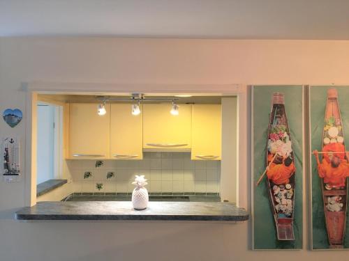 eine Küche mit gelben Schränken und einem Regal mit einer weißen Flasche in der Unterkunft Superbe appartement terrasse in Levallois-Perret