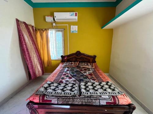 um quarto com uma cama num quarto com paredes amarelas em Mullai Home Stay em Salem