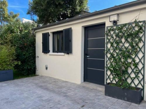 un garage con una porta nera e una finestra di Studio neuf s/jardin, très calme a Colombes