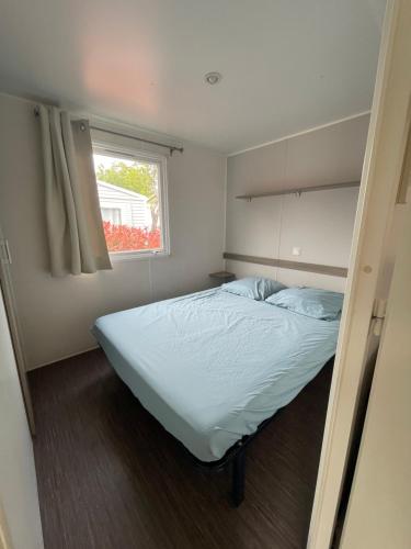a small bedroom with a bed and a window at Mobil Home de Marine in Port-la-Nouvelle
