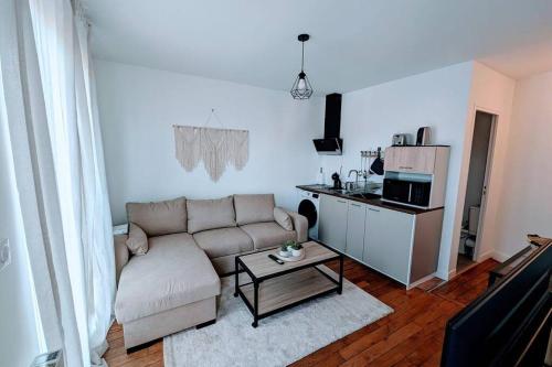 uma sala de estar com um sofá e uma mesa de centro em 2 pièces Cosy avec vue Panoramique et Balcon ! em Rosny-sous-Bois