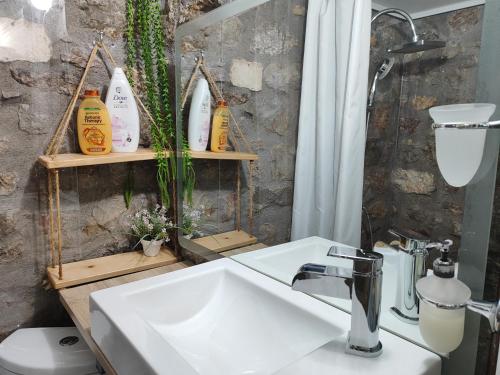 a bathroom with a white sink and a shower at Naupactus unique harbor apartment in a stone house! in Nafpaktos
