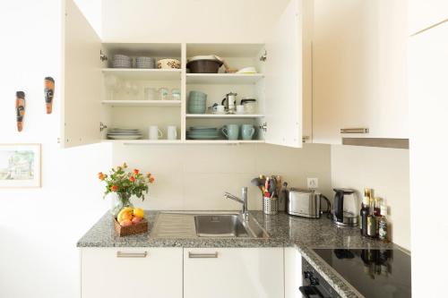 una cocina con armarios blancos y fregadero en AM3Office apartment with view, Parking and contactless check-in Vevey Montreux en Vevey