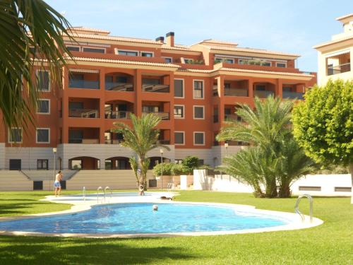 a swimming pool in front of a building at Jardinas de les Marinas in Denia