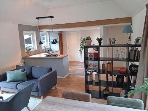 a living room with a blue couch and a kitchen at Ruim huisje op een prachtige plek in Hemrik