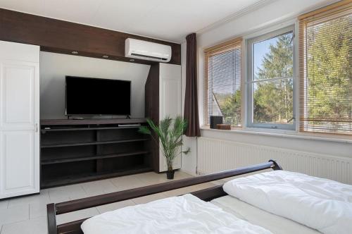 a bedroom with a flat screen tv and a bed at Wellnesshuis Drenthe in Schoonloo