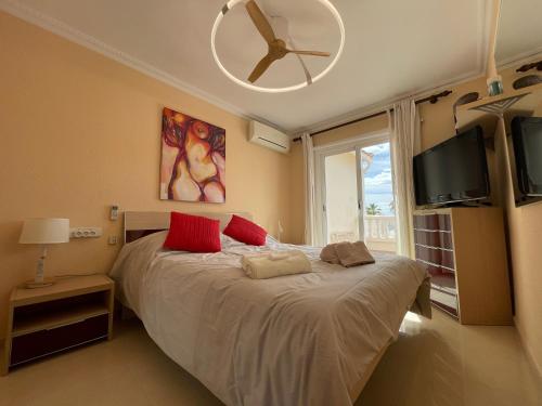 a bedroom with a bed with red pillows and a flat screen tv at Bungalow on the beach 15 minutes from Valencia in Valencia