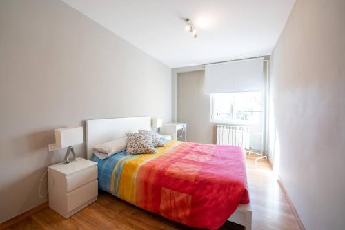 een slaapkamer met een bed met een kleurrijke deken bij Apartamento GO Felipe II Center in Valladolid