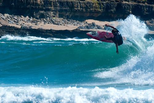 una persona montando una ola en una tabla de surf en el océano en Casa Da Avó 2 en Ericeira