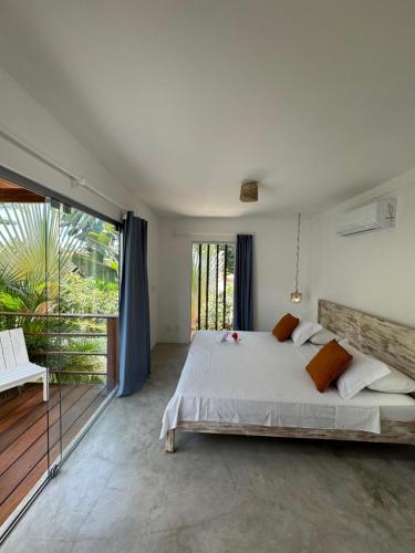 a bedroom with a large bed and a balcony at La Réserve Villa REPOUSO PARAISO in Pipa