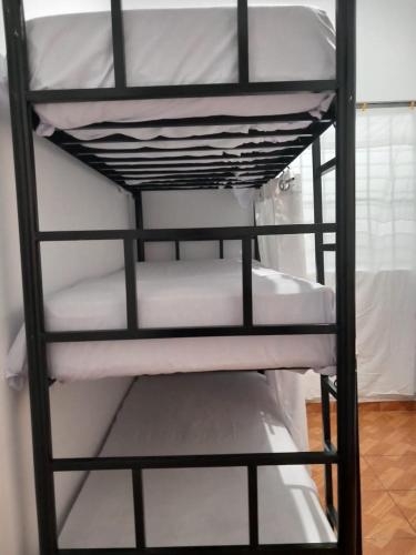 a black bunk bed with white sheets on it at PAZ Y BIEN BACKPACKERS - HABITACIÓN COMPARTIDA MIXTA EN MIRAFLORES DE FAMILIA EVANGÉLICA CON PRINCIPIOS Y VALOREs in Lima