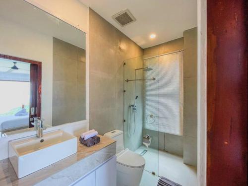 y baño con lavabo, aseo y ducha. en Ocean Wave Lombok - 4 BR infinity pool villa, en Selong Belanak