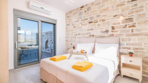 a bedroom with a white bed and a stone wall at Villa Ovgoro in Kamilari