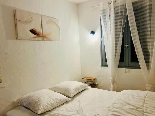 een witte slaapkamer met een bed en een raam bij Appartement T2 vue mer in Porticcio