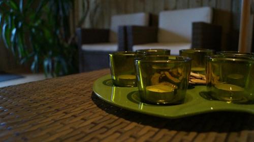 a green plate with several glasses on a table at À L'orée Du Bois in Pommerit-le-Vicomte