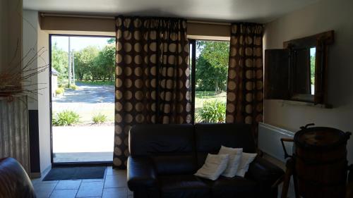 a living room with a couch and a sliding glass door at À L'orée Du Bois in Pommerit-le-Vicomte