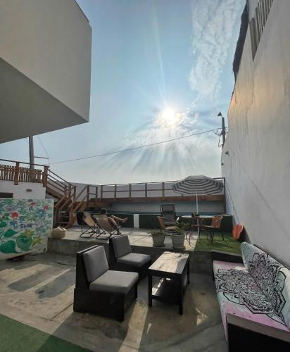 patio con divani, tavolo e ombrellone di El Templo Surf House a Punta Hermosa