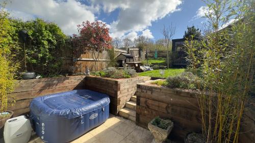 a garden with a blue trash can in a yard at Five Farthings Stylish cottage in Littleworth