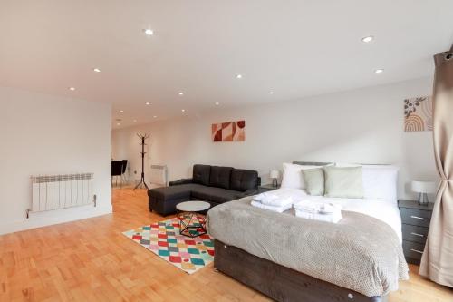 a bedroom with a large bed and a couch at Charming Studio Flat in Kingston KT2, London in Kingston upon Thames