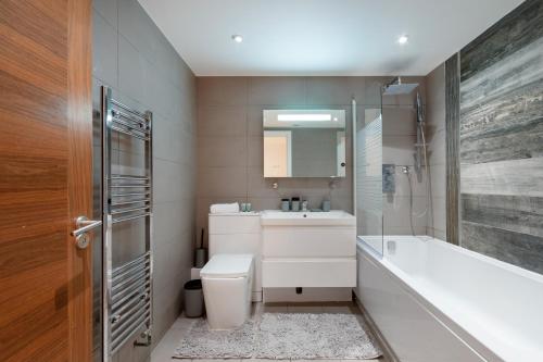 a bathroom with a tub and a toilet and a sink at Charming Studio Flat in Kingston KT2, London in Kingston upon Thames