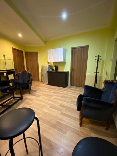 a living room with blue chairs and a kitchen at Siqvaruli in Tbilisi City