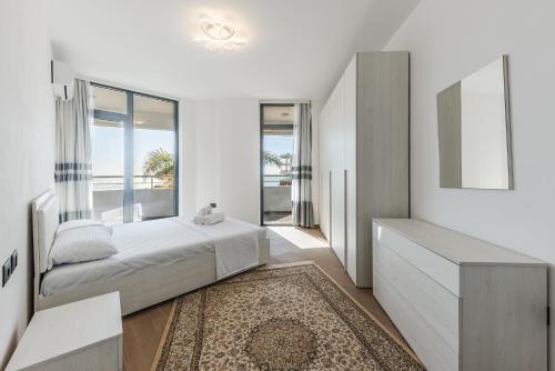 a white bedroom with a bed and a large window at Hill Side Suite by PS in Durrës