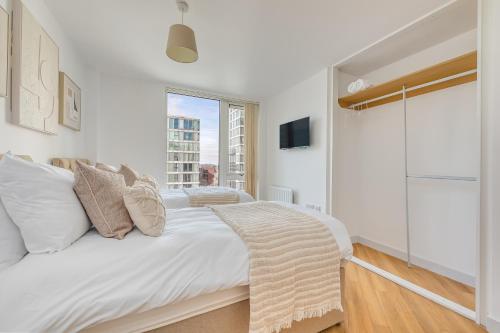 a white bedroom with a large bed with a window at Stunning City Centre Apartment with Balcony, Free Parking, Fast Wifi and SmartTVs by Yoko Property in Milton Keynes