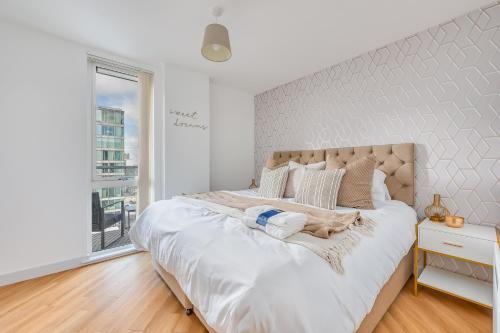 a large white bed in a white bedroom with a window at Stunning City Centre Apartment with Balcony, Free Parking, Fast Wifi and SmartTVs by Yoko Property in Milton Keynes
