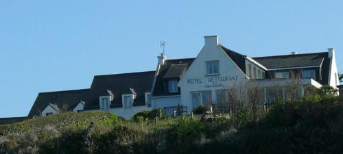 a building on top of a hill next to a house at Hôtel-Restaurant des Iles in Houat