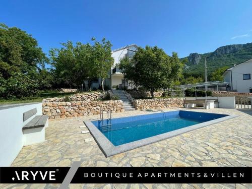 a swimming pool in a yard with a stone wall at ARYVE® Boutique-Ferienvilla mit Meerblick, Pool und Design-Interieur in Bribir in Bribir