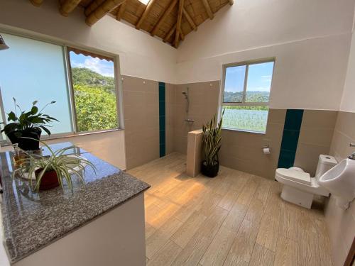 a bathroom with a toilet and a sink and windows at Casa Cosmonova in Puerto López