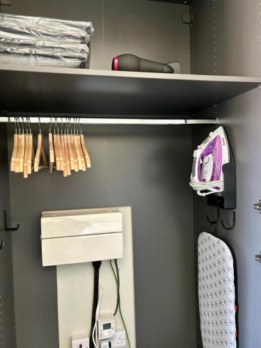 a closet with a shelf with a hair dryer at White Oaks Sussex in Twineham