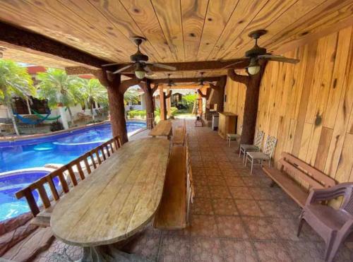 a large wooden table next to a swimming pool at Agradable y Lujosa casa de campo con piscina in Huité