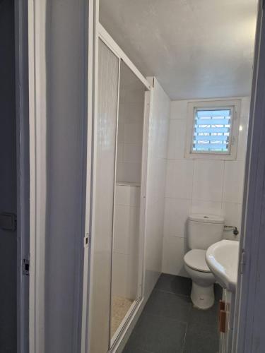 a bathroom with a toilet and a sink and a window at Alojamiento Vora - Sitges in Barcelona