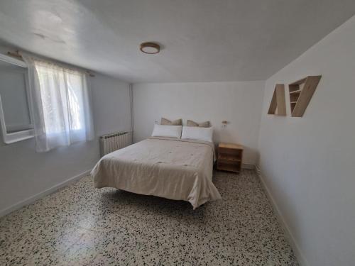 1 dormitorio con 1 cama con sábanas blancas y ventana en Alojamiento Vora - Sitges, en Barcelona