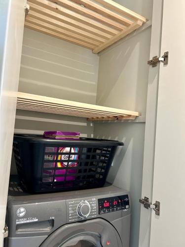 a washing machine in a laundry room with a shelf at White Oaks Sussex in Twineham