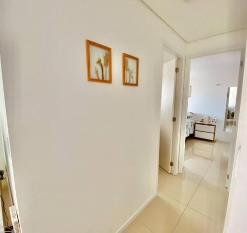 a white hallway with two pictures on a wall at Apartamento Charme Benfica in Fortaleza