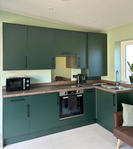 a kitchen with green cabinets and a microwave at White Oaks Sussex in Twineham