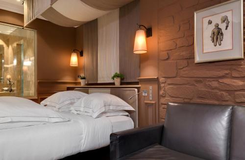 a bedroom with a white bed and a chair at Hôtel du Château & Spa - Teritoria in Carcassonne