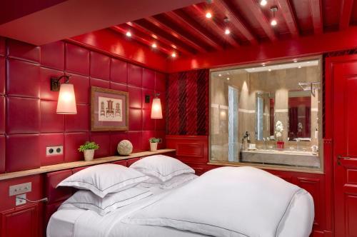 a red bedroom with a bed and a sink at Hôtel du Château & Spa - Teritoria in Carcassonne
