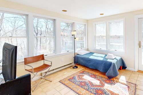 a bedroom with a bed and a chair and windows at Woods Hole Hideaway in Falmouth