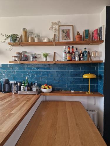 cocina con paredes azules y mesa de madera en Charming bedroom in artist studio en Londres