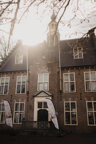 a brick building with a clock tower on top of it at Hotel het Oude Raadhuis in Castricum